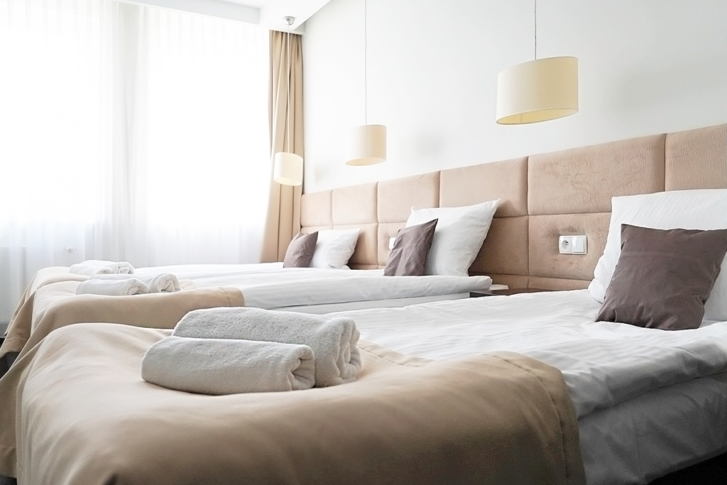 widok na pokój trzyosobowy w wariancie standard z widocznymi trzema łóżkami w jasnej kolorystyce