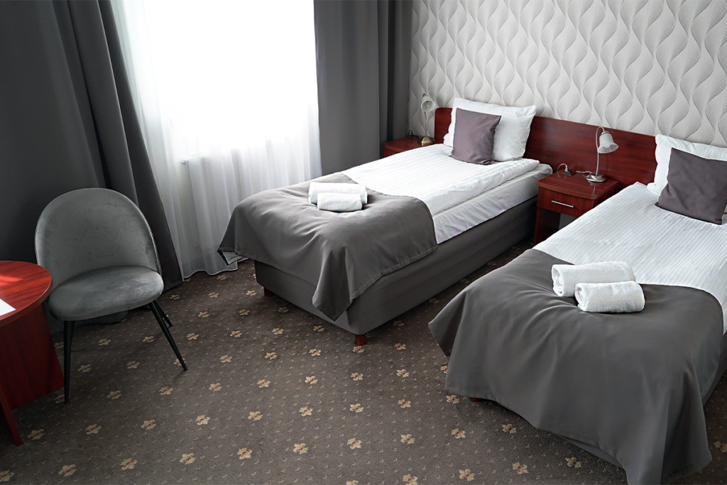 widok na pokój dwuosobowy w wariancie komfort z dwoma pojedynczymi łóżkami i krzesłem