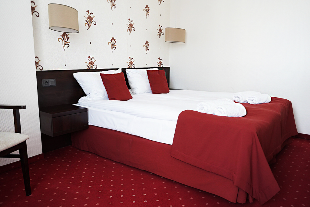 widok na dwuosobowy pokój delux w bydgoskim hotelu maraton z jednym lozkiem dwuosobowym w biało-czerwonej kolorystyce