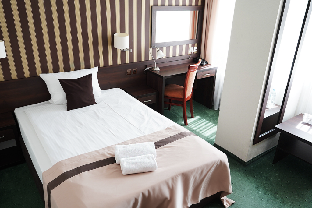 widok na jednoosobowy pokój w wariancie standard w Hotelu Maraton z łóżkiem biurkiem i lustrem